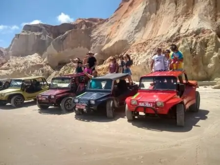 Grupo de passeio de buggy na praia com falésias atrás