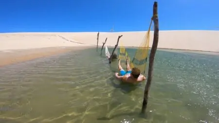 Duas pessoas relaxando em duas redes em uma lagoa entre as dunas