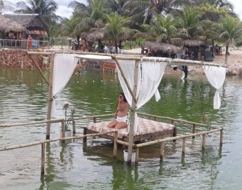 Barraca Oásis de fundo e mulher numa cama no meio da Lagoa