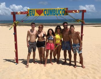 Família tirando foto com a placa escrita "Eu amo Cumbuco"