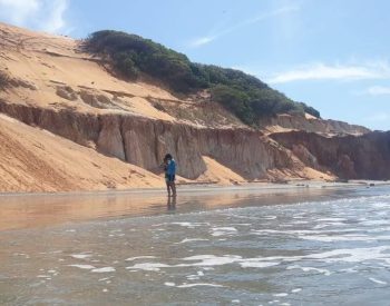 Duas pessoas caminhando na beira do mar