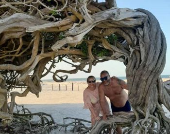 Duas pessoas numa praia debaixo de uma árvore