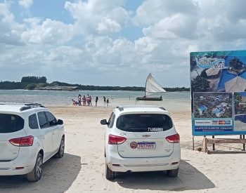 Dois carros, uma jangada e a lagoa do Paraíso de fundo