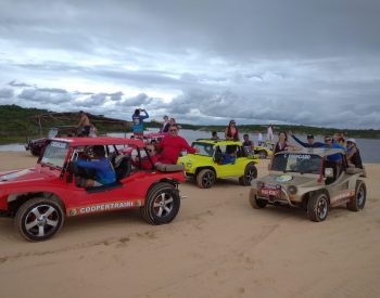 Várias pessoas andando em sete buggys em uma duna