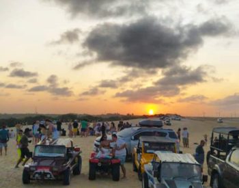 Pessoas acompanhando por sol na duna