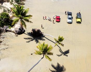 Pessoas passeando na beira do mar com veículos