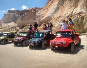 Grupo de passeio de buggy na praia com falésias atrás