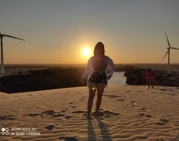 Mulher tirando foto com pôr do sol na duna