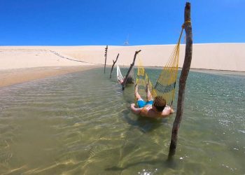 Duas pessoas relaxando em duas redes em uma lagoa entre as dunas