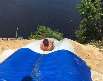 Pessoa descendo tobogã na duna e indo direto para o lago