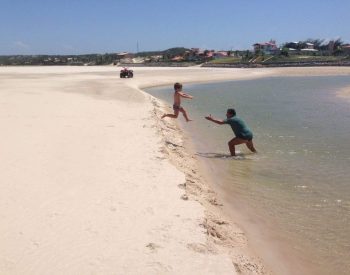 Criança pulando nos braços de um homem na praia